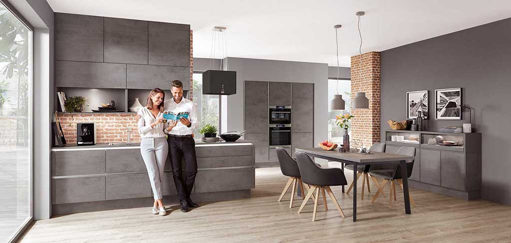 Paar / Mann und Frau in Nobilia Küche Riva mit matter Küchenfront in grau, ohne Griffe und mit Esstisch- Die Küchenwelt Thomas Brag in Duisburg und Bocholt