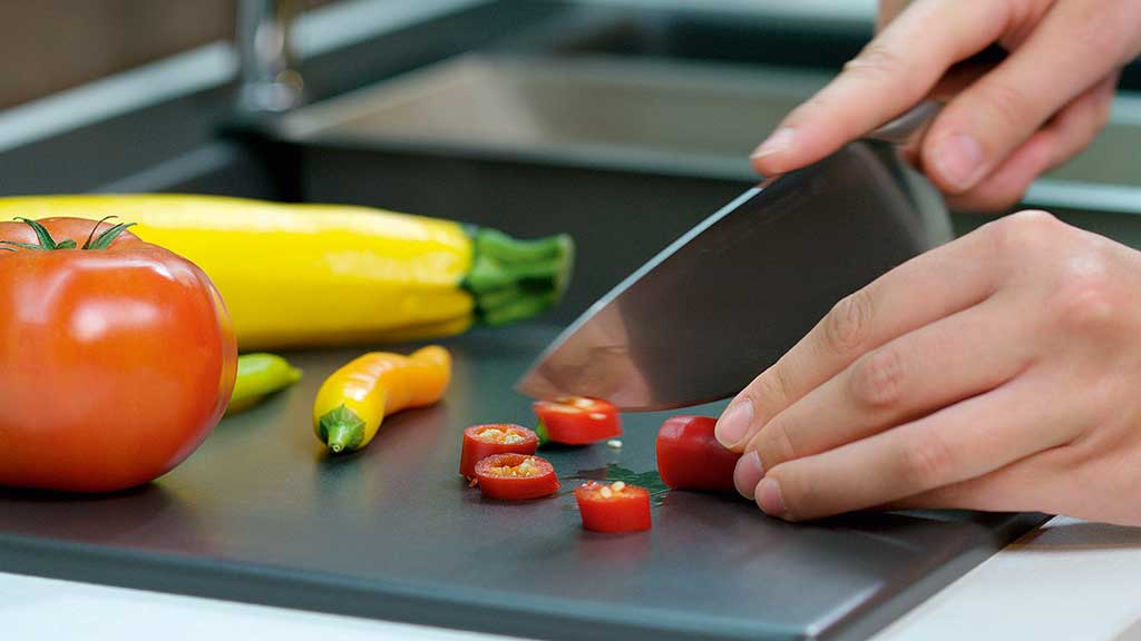 Frau schneidet Chilischote auf schnittfester Systemceram Keramikspüle - Die Küchenwelt Thomas Brag in Duisburg und Bocholt